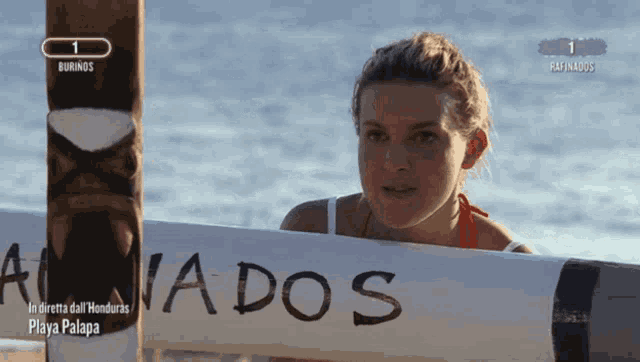 a woman stands in front of a sign that says ' nados ' on it