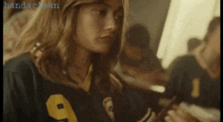 a girl wearing a jersey with the number 9 on it is looking at something .