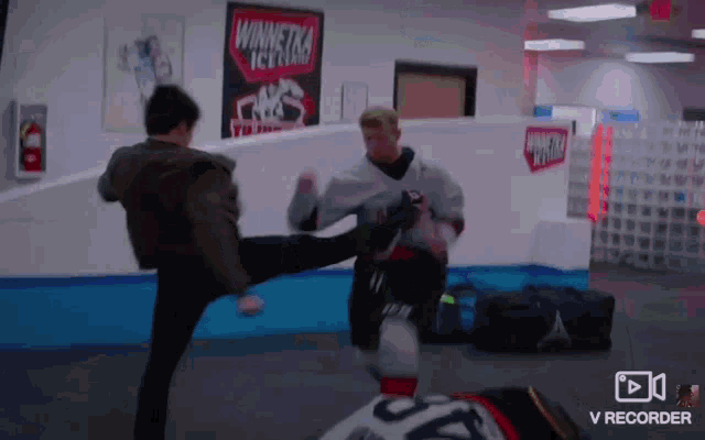 a man kicking another man in a gym with a sign that says winnetka ice cream