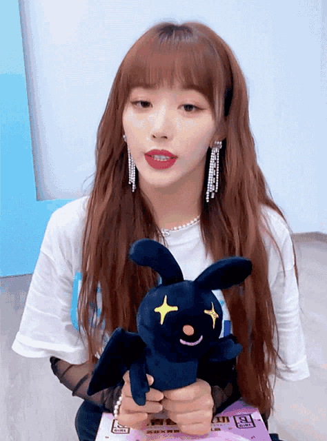 a girl is holding a stuffed animal that has a bat on it 's face