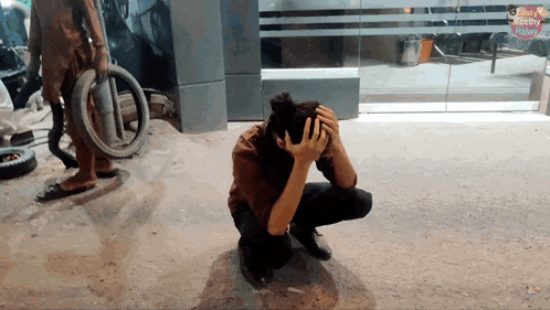 a person kneeling down with their head in their hands in front of a glass door that says " read monthly "