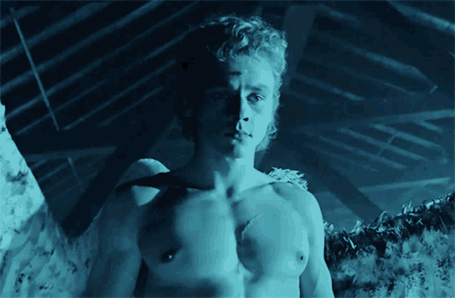 a man without a shirt is standing in a blue room