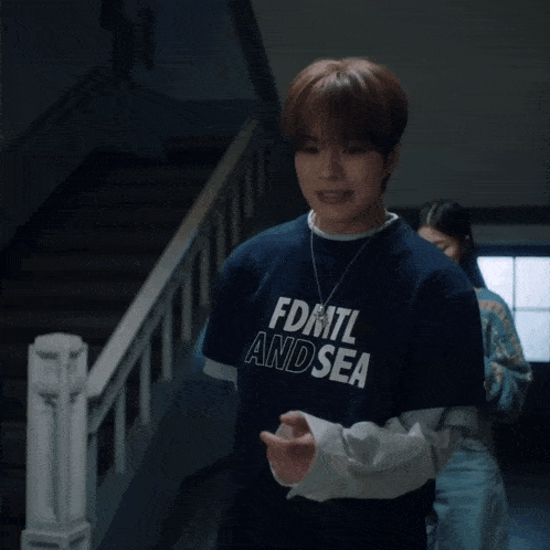 a young man wearing a blue shirt with the letter s on the front