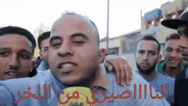 a group of men are standing around a man with arabic writing on his face