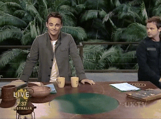 a man stands in front of a table with a sign that says live on it