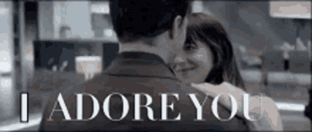 a man and a woman are hugging each other with the words `` i adore you '' written on the bottom of the image .