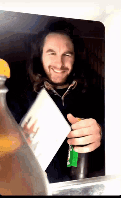 a man in a black jacket is holding a bottle of heineken