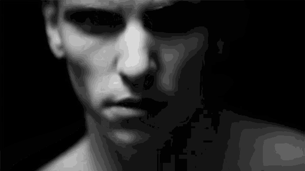 a black and white photo of a man 's face without a shirt in the dark .