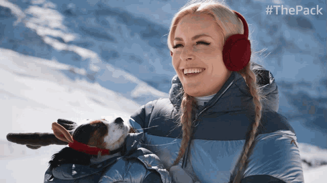 a woman wearing red ear muffs holds a small dog in her arms