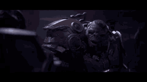 a video game character in armor is talking to another character in a dark room .