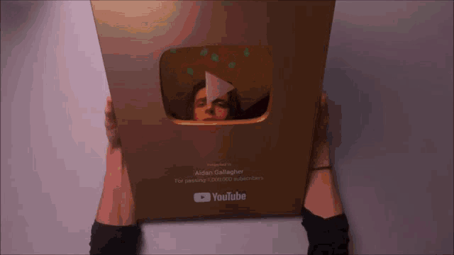 a person is holding a youtube plaque in front of their face