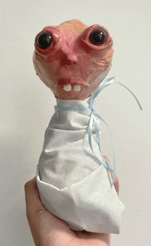 a person is holding a puppet wrapped in a white blanket