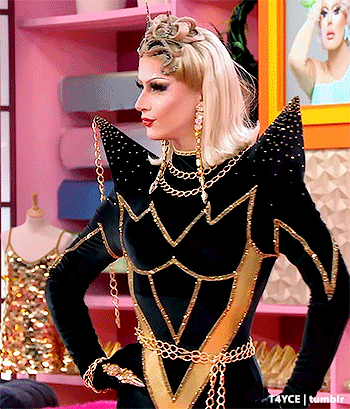 a drag queen wearing a black and gold outfit with a crown on her head