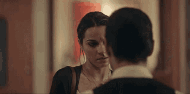 a man and a woman are looking at each other in a hallway .