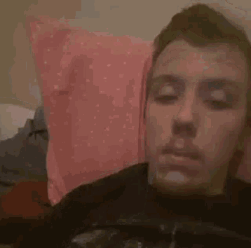 a man is blowing a cloud of smoke out of his mouth while laying on a bed .