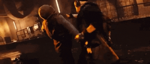 a group of people are fighting each other in a dark room at night .