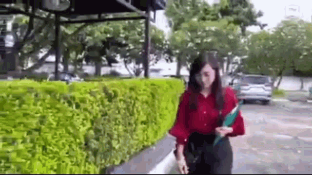 a woman in a red shirt and black pants is walking down a street .