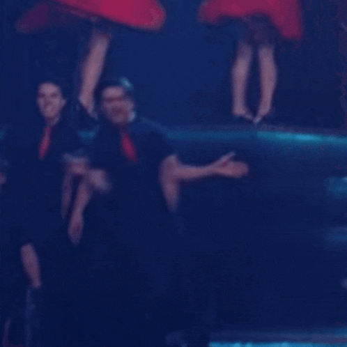 a man in a black shirt and red tie is dancing in front of a crowd