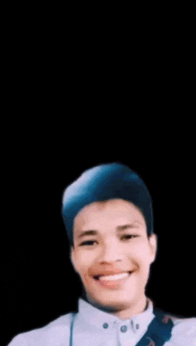 a young man is smiling in front of a sign that says assalamualaikum