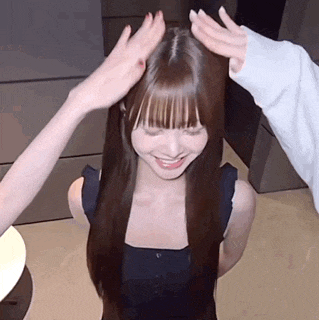 a woman with long hair is being patted on the head by two other people .