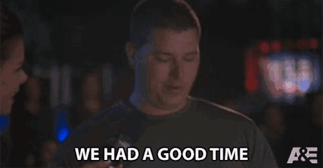a man is talking to a woman and saying `` we had a good time '' while holding a beer .