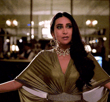 a woman wearing a necklace and earrings is standing in front of a mirror