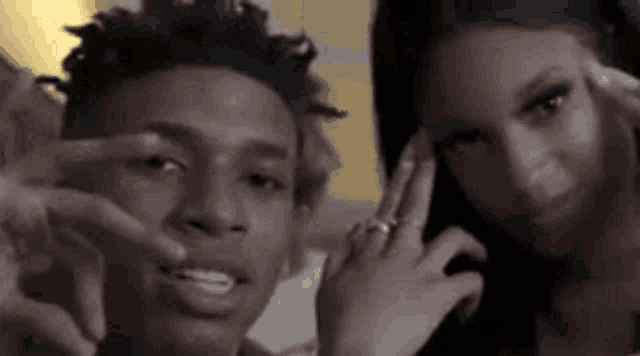 a man and a woman are posing for a picture together . the man is wearing a ring on his finger .