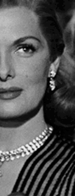 a close up of a woman wearing a necklace and earrings .