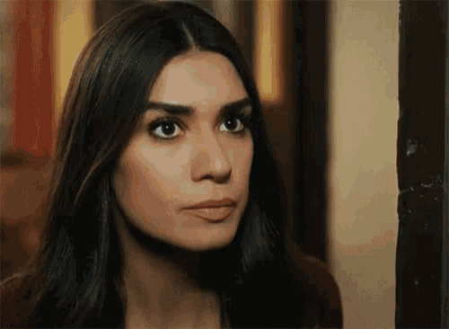 a close up of a woman 's face with long dark hair looking at the camera .