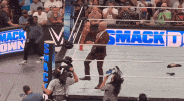 a man in a suit is dancing in a wrestling ring with a smack down sign behind him