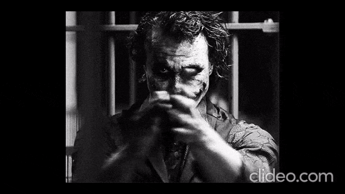 a black and white photo of the joker from the dark knight rises pointing his finger at the camera .