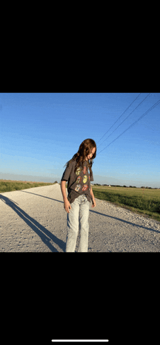 a person wearing a rolling stones t-shirt stands on a dirt road