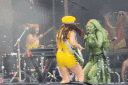 a woman in a yellow outfit is standing next to a woman in green