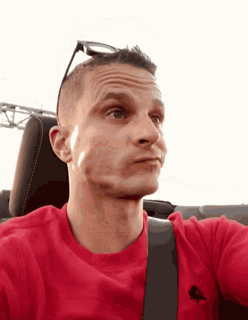 a man wearing sunglasses and a red shirt with a black eagle on it