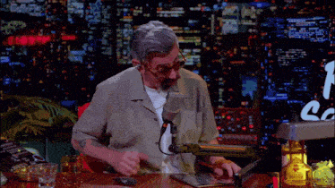 a man is sitting at a desk with a microphone and a bottle of tequila