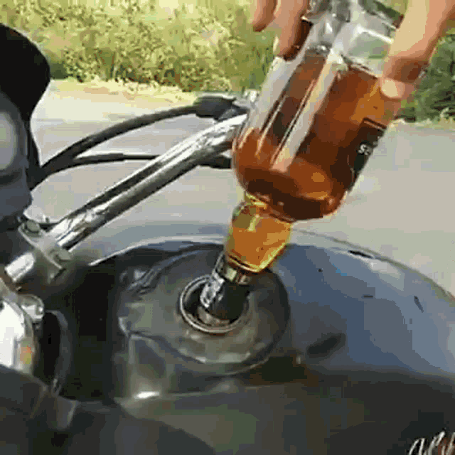 a bottle of jack daniel 's whiskey is poured into a motorcycle tank