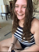 a woman in a striped swimsuit is sitting on the floor smiling .