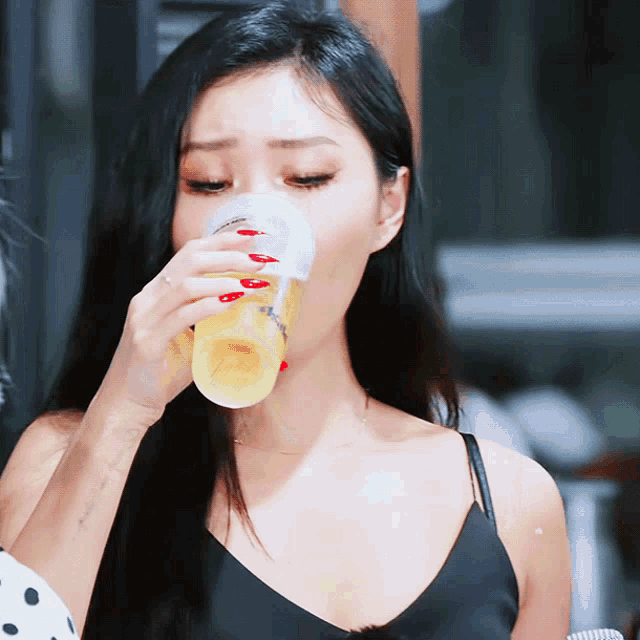 a woman in a black tank top is drinking from a cup that says ' coca cola ' on it