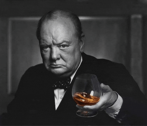 a man in a tuxedo and bow tie holds a glass of whiskey