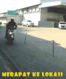 a man is riding a motorcycle down a street with the words " merapat ke lokasi " written on the bottom