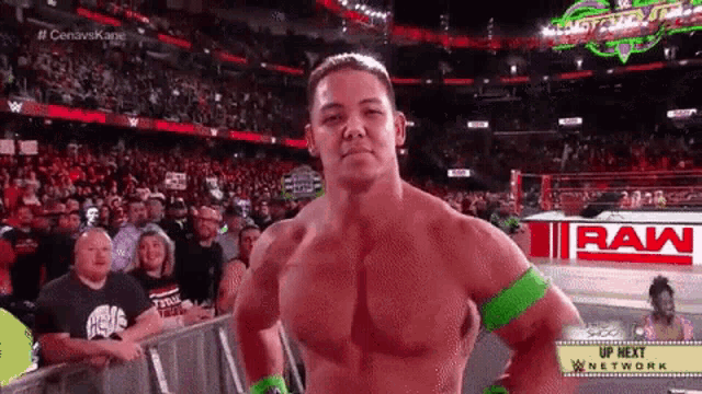 a wrestler is standing in front of a crowd in front of a raw logo