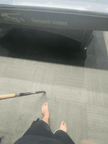 a person standing in front of a pool table that says " tournament standard "