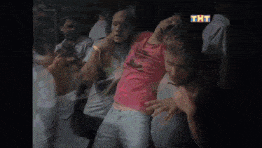 a group of people are dancing in a dark room with a tnt logo in the corner
