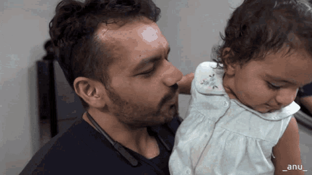 a man holding a baby with the name anu on the bottom left