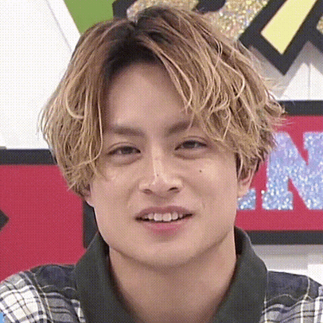 a close up of a man 's face with blonde hair and a plaid shirt .