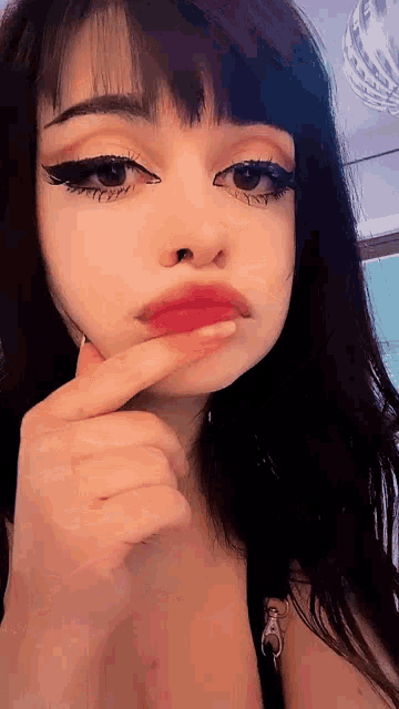 a close up of a woman 's face with her finger on her mouth .