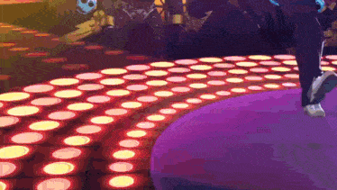 a person walking on a dance floor with circles of lights on it