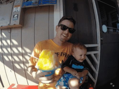 a man holding a baby wearing a shirt that says ' etria ' on it
