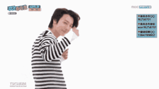 a man in a black and white striped sweater is giving a peace sign