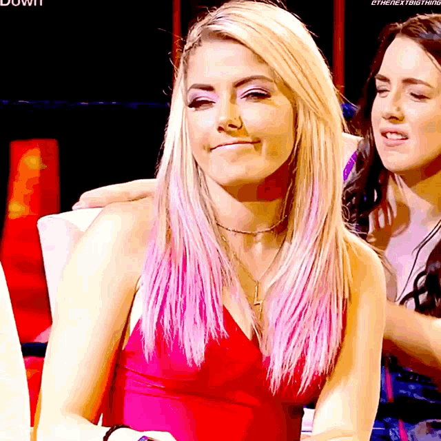 a woman in a red dress is sitting next to another woman with the word down on the bottom